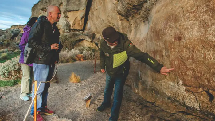 Guía turístico explicando la geología, glaciología y flora nativa de la Patagonia a orillas del lago